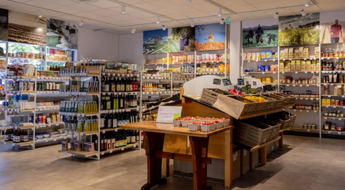 Interior view of a well-stocked store with shelves full of food and a table with fresh strawberries.