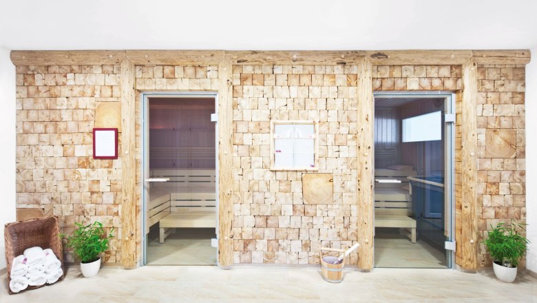 Two sauna cabins with wooden walls and glass doors in a wellness area.