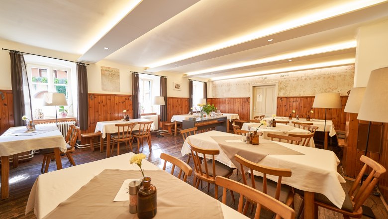 Interior view of a cozy dining room with wooden furniture and white tablecloths.