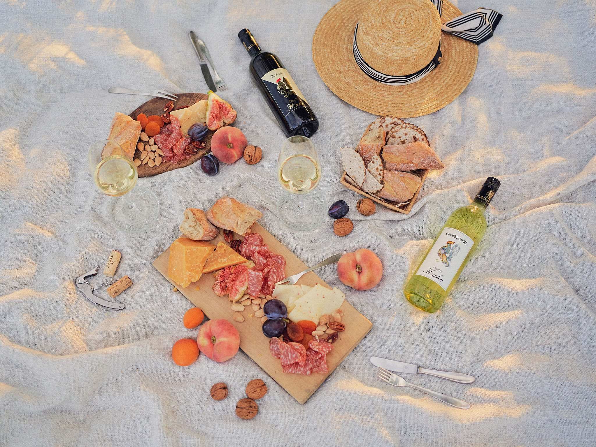 Picnic with wine, cheese, bread and fruit on a blanket.