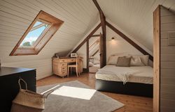 Rustic stone house with wooden door, bench and flowers in the foreground.