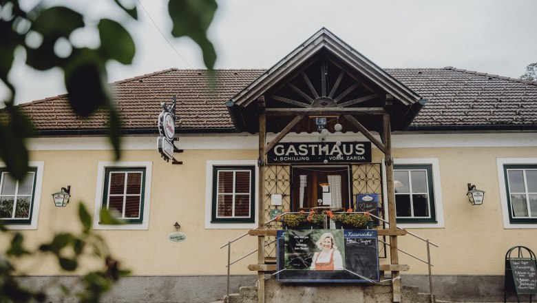 Entrance to a traditional inn with wooden veranda and advertising board.