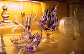 Various colorful glass vases on a wooden shelf.