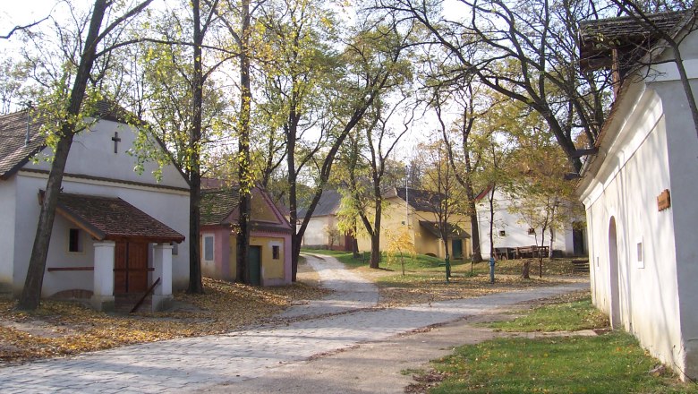 A quiet village square with small, traditional buildings and trees in the fall.