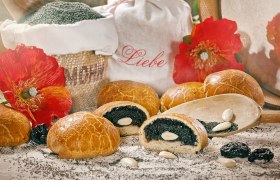 Poppy seed roll decorated with almonds, poppy seeds and red flowers.