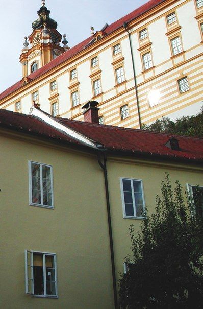 Yellow building with a red roof in front of a monastery.