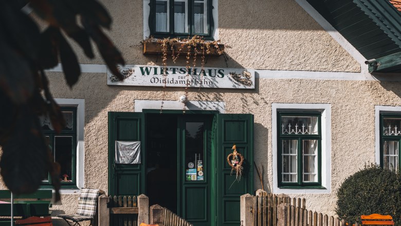 Entrance to a traditional inn with green doors and windows, decorated with a wreath.