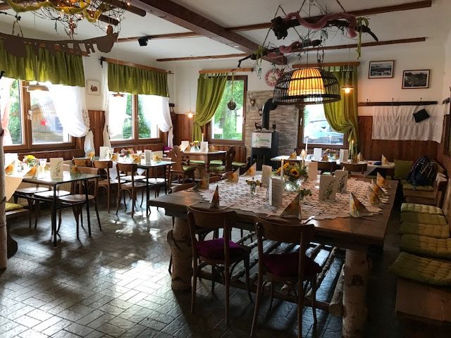 Cozy dining room with wooden furniture, decorated with flowers and tablecloths.