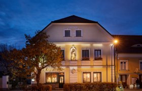 St. Florian Inn at dusk with illuminated façade and statue.