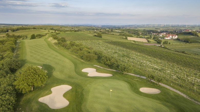 Aerial view of a golf course with sand bunkers and surrounding vineyards.
