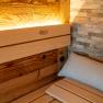 Interior view of a sauna with wood paneling and stone wall.