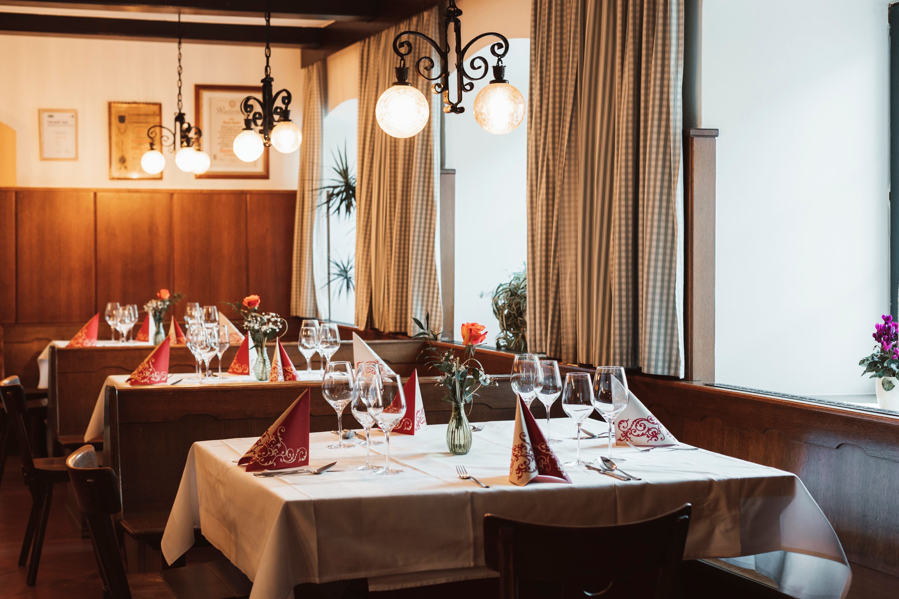 Cozy restaurant with laid tables, wine glasses and flower vases.