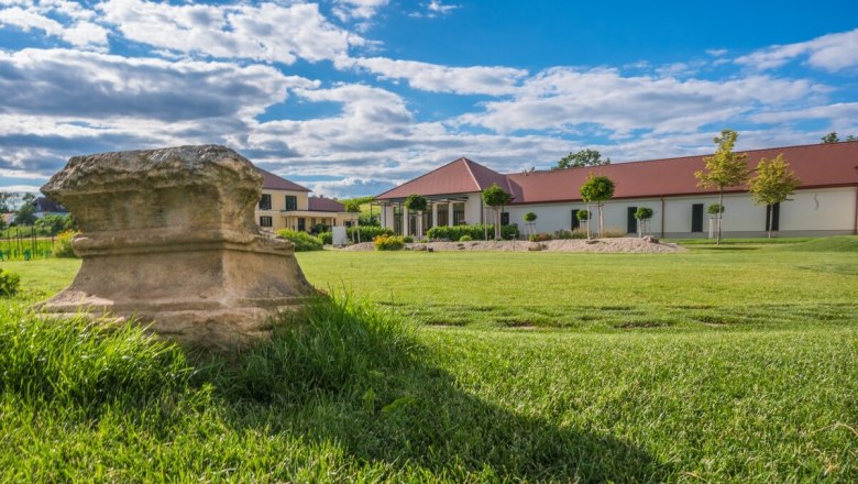 Winery with lawn and antique stone in the foreground.