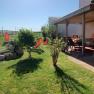A sunny garden with lawn, shrubs, sun loungers and a covered terrace with table and chairs.