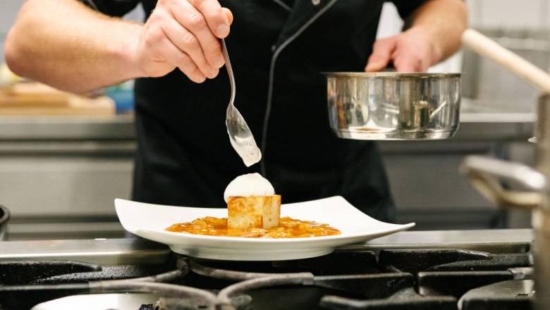 A chef decorates a dish in a professional kitchen.