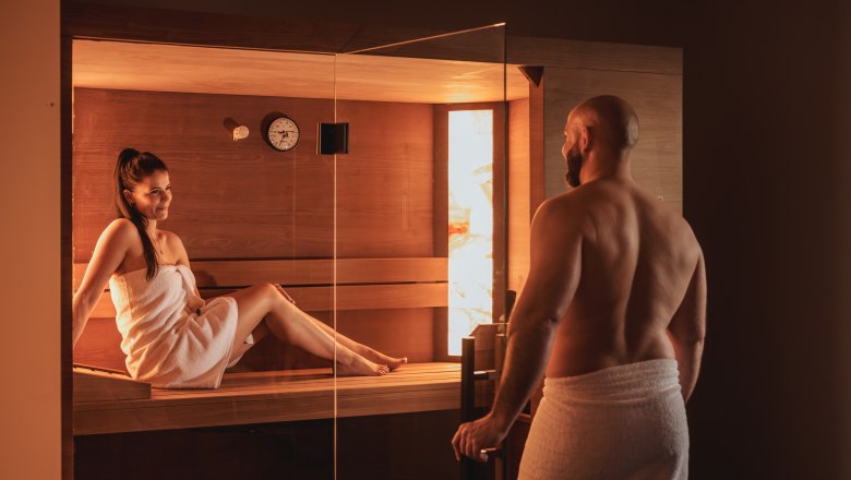 A man and a woman in towels in a sauna.