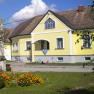 Yellow guest house with flower bed and bicycles in front.