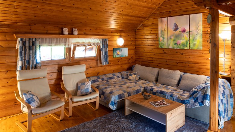 Cozy living room in a wooden hut with sofa, armchairs and decoration.
