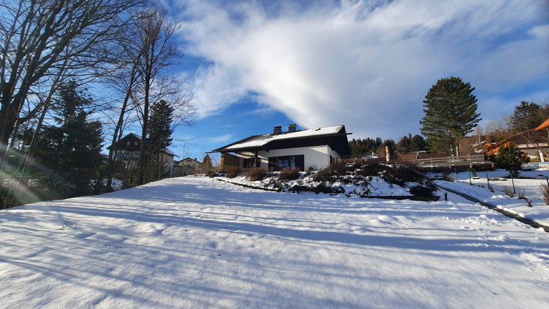 Belle Air Lodge in winter, © Christoph Gierlinger Winter landscape with a house in the snow, surrounded by trees and blue sky.