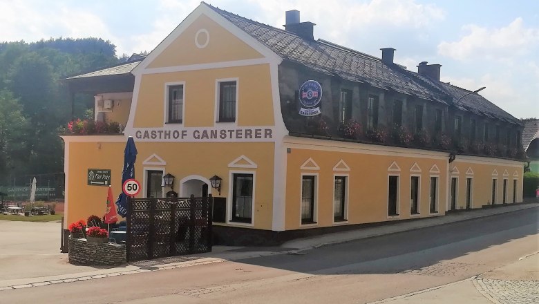 Yellow building of the Gasthof Gansterer in Zöbern with flower boxes and traffic sign.