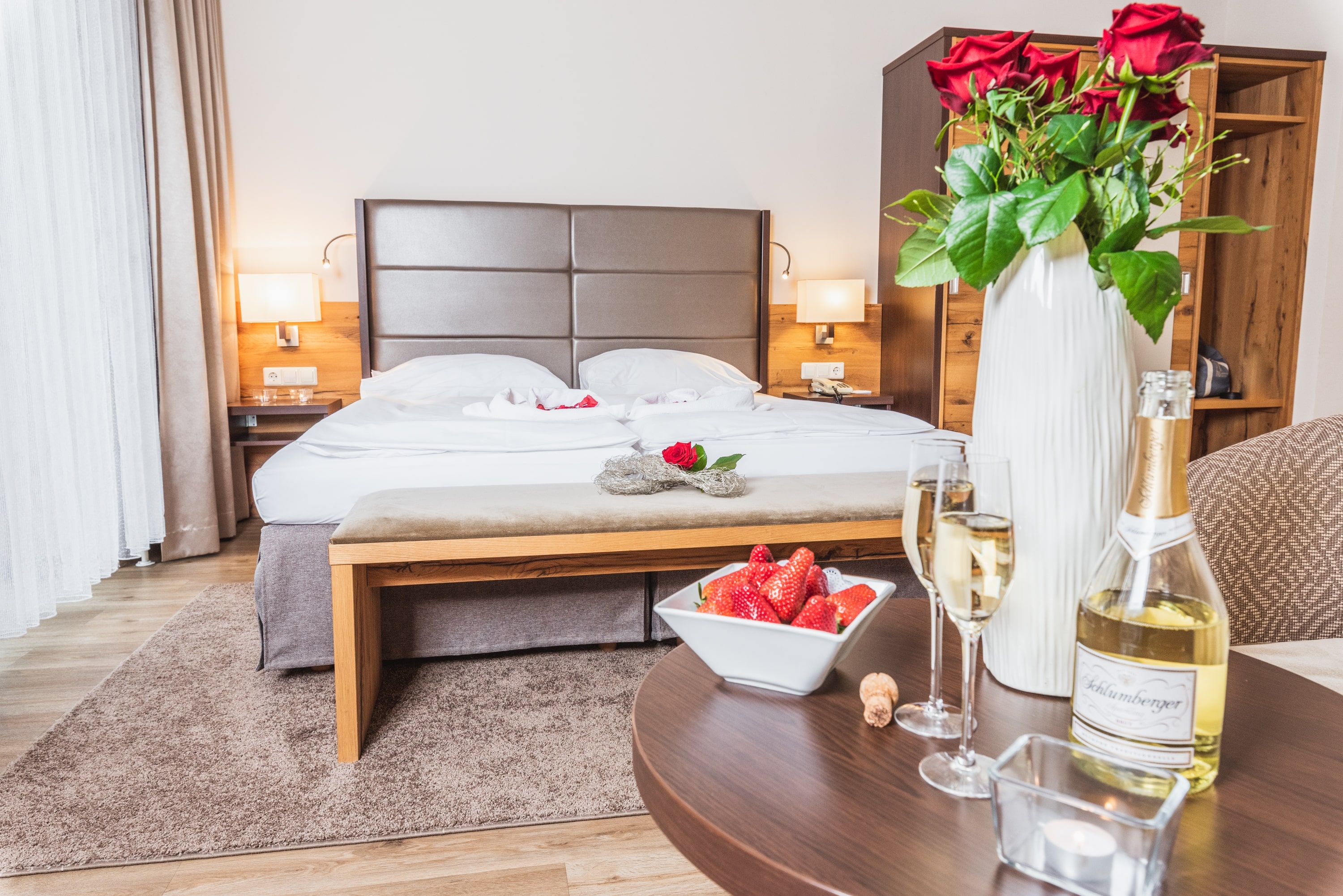 Double room at Hotel Schneeberghof with bed, roses, sparkling wine and strawberries.