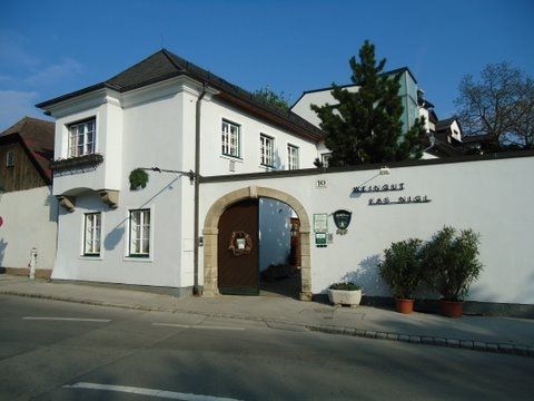 Entrance gate to the Kas-Nigl winery with white façade and plants.