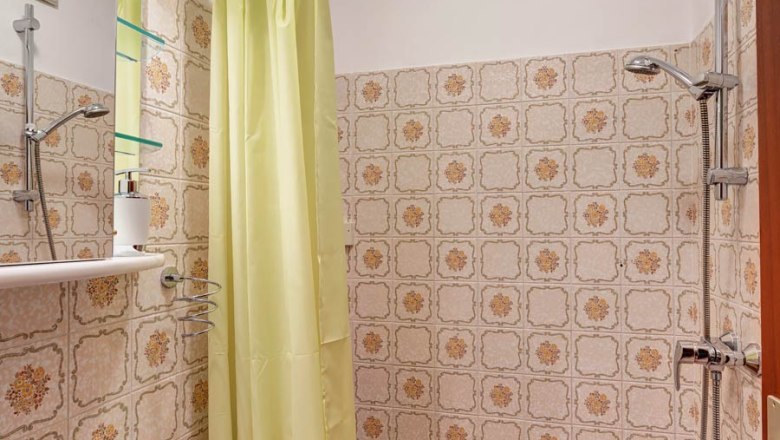 Small bathroom with yellow shower curtain, washbasin and patterned tiles.