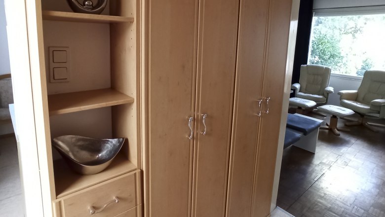 Wooden cupboard with shelves and drawers in one room.