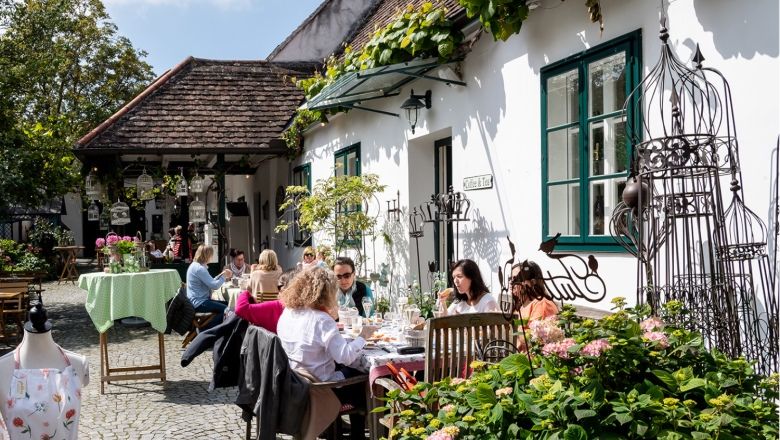 People sit at tables outside in a cozy courtyard.
