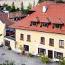 A traditional guest house with a yellow façade and red roofs in a quiet street.
