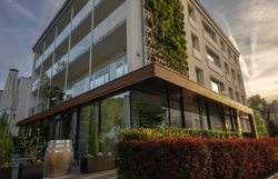 A stylishly furnished hotel room with a large red shoe as a bookshelf, antique chairs, a table and a floor lamp.