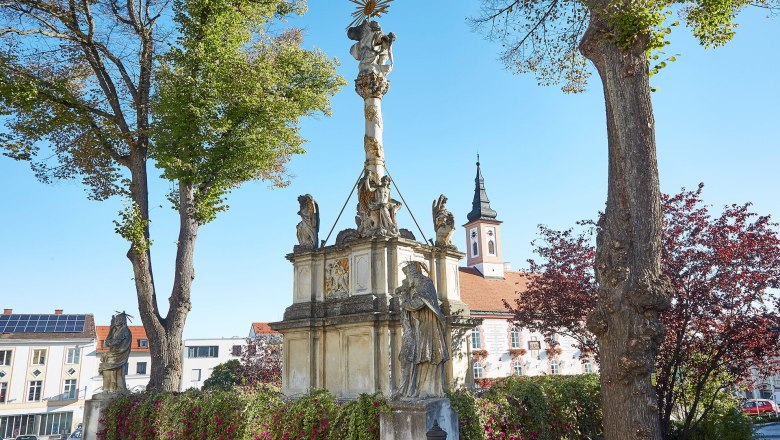 An impressive monument stands in the picturesque walled town of Waidhofen an der Thaya, surrounded by lush greenery and colorful flowers. The radiant sun bathes the scenery in warm light and invites you to enjoy the historical atmosphere and the beauty of the surroundings.