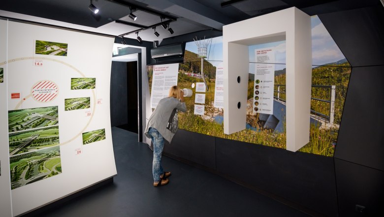 A person looks at an exhibition in a modern information center with pictures and texts on the walls.