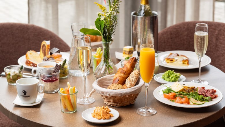A laid breakfast table with various dishes, drinks and flowers.