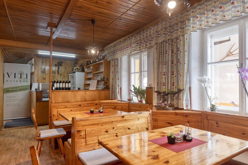 Cozy wine tavern with wooden furniture and decorative curtains.