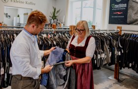 Two people are looking at an item of traditional clothing in a clothing store.