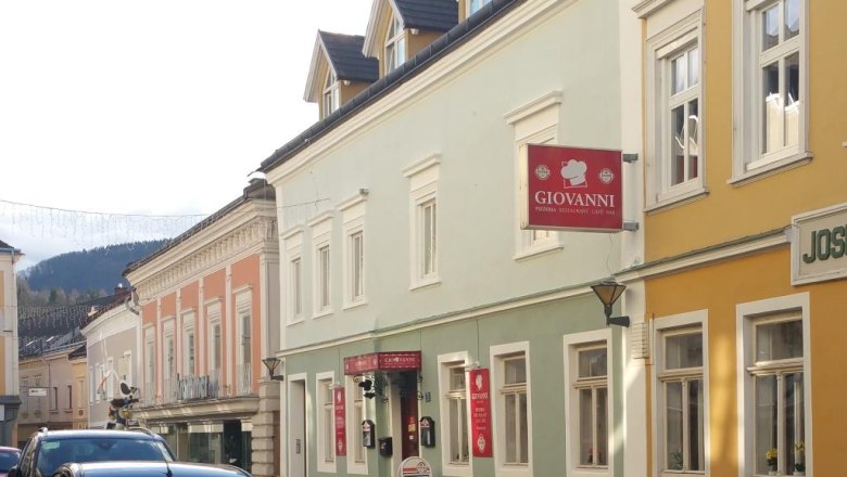 Street scene with colorful buildings and a sign with the inscription 'Giovanni'.