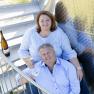 A man and a woman are sitting on a metal staircase with wine glasses in their hands.