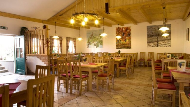 Interior view of a cozy wine tavern with wooden furniture and decorative paintings on the walls.