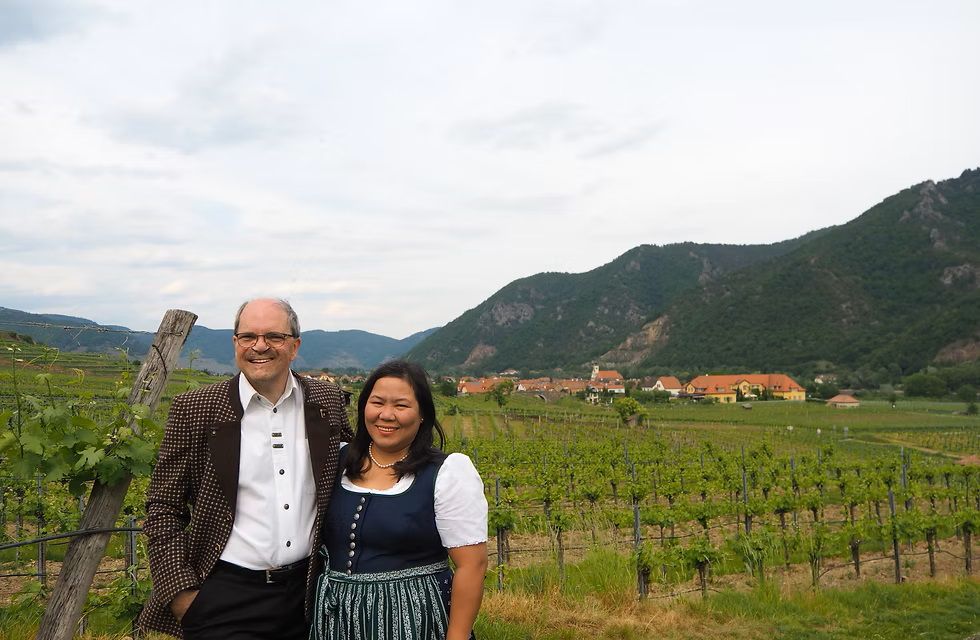 A man and a woman in traditional costume in the background grapevines