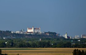 View of Bratislava Castle and the city in the background, surrounded by green countryside.