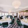 Elegant restaurant with round tables, green chairs and chandeliers.