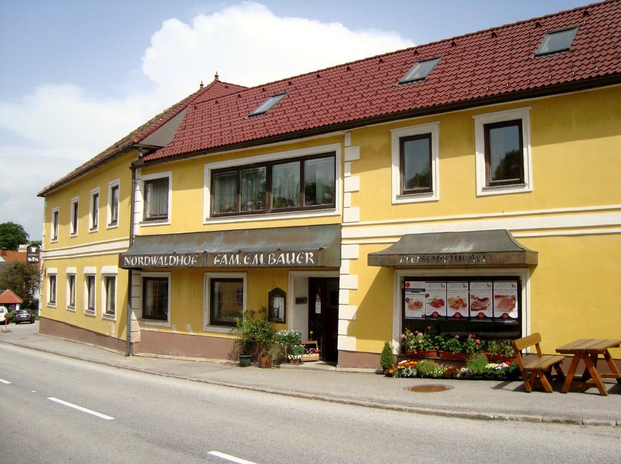 Yellow building with red roof and signs 'Nordwaldhof' and 'Fleischhauerei'.