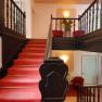 Hotel staircase with red carpet and dark wooden banister.