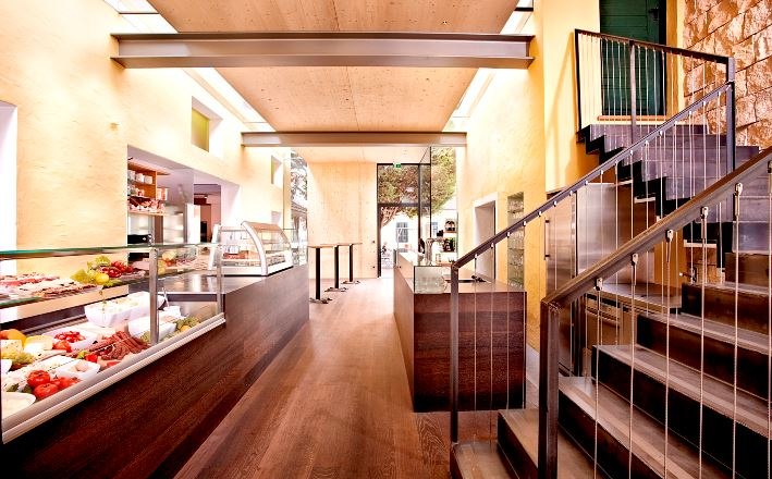 Interior view of a modern buffet with wooden floor, stairs and glass cabinets.