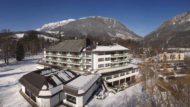 Parkhotel Hirschwang in winter with snow-covered mountains in the background.