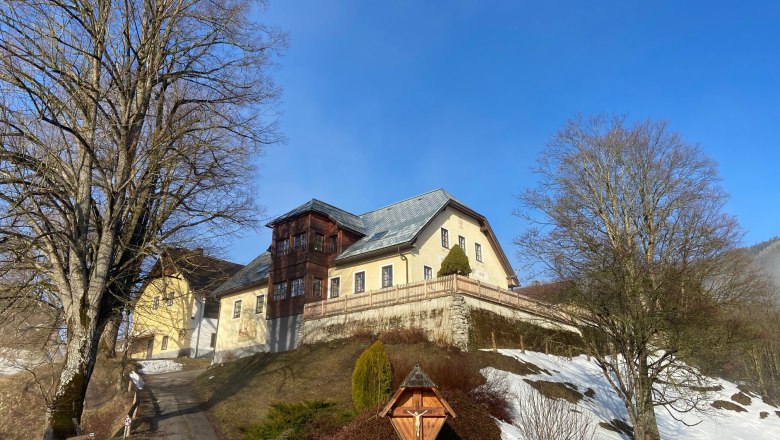 Garhof in winter, © Wiener Alpen A large building on a hill with snow and bare trees in the foreground.