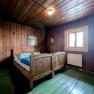 Rustic double room with wooden walls and furniture, two single beds, window and heating.