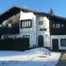 A two-storey house with wooden cladding and snow in the foreground.