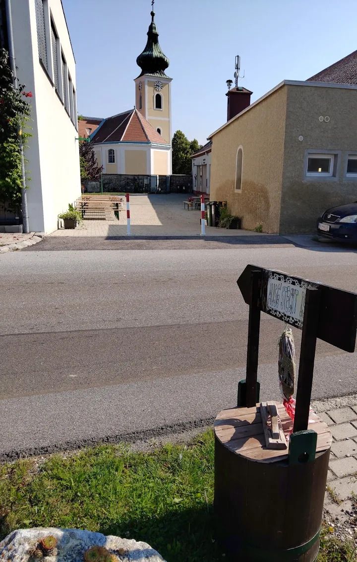 Buschenschank (typical tavern) Thaller Wolfsthal, view into the courtyard with wine tables, in the background you can see a church 